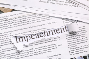 Obraz premium Torn piece of paper with word IMPEACHMENT on newspapers, closeup