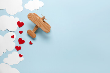 Wooden airplane with paper hearts and clouds on blue background. Valentine's Day celebration