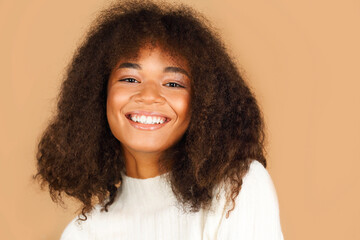 Studio shot of gorgeous cheerful african american young woman with curly hair smiling at camera