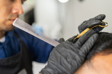 Barber using comb and scissors cutting the hair of client