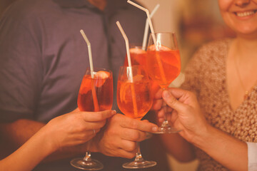 Group of friends cheers with aperol spritz in restaurant