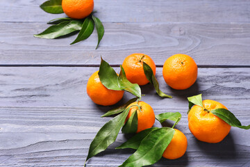 Sweet mandarins with leaves on blue wooden background