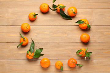 Frame made of sweet mandarins and leaves on wooden background