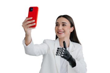 European brunette handicapped girl in white suit holding phone, making video call  showing thumb up gesture by biomechanical prosthesis at office. Cute disabled female toothy smiling, making selfie.