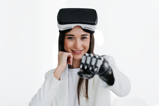 European cute brunette girl with bionic arm in white suit with vr glasses on her forehead, makes punch by her bionic artificial hand. Woman with biomechanical prosthesis at office. Cyborg human.