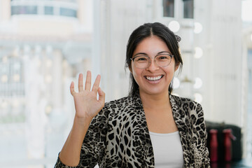 Young Latina woman portrait, waving and smiling.