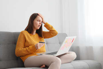 Technology and financial transactions. Shocked Caucasian brown haired woman working with laptop and...