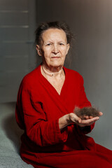 balding grandmother from chemotherapy. hair loss in a woman due to a cancerous tumor. a piece of hair in grandmother's hands because of cancer