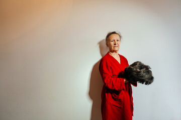 a woman with an artificial wig on her head on a light background. a woman suffering from a...