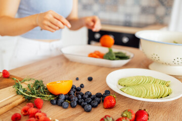 A young girl is preparing a vegan breakfast in the kitchen. Close-up of a plate with avocado,...
