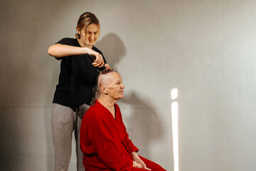 shaving woman because of a cancerous tumor. removal of hair on the head with an electric razor before surgery. hair loss due to cancer. shaving the grandmother's head before a course of chemo therapy