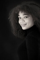 African beauty. Smiling young african-american woman in black clothes isolated on dark background