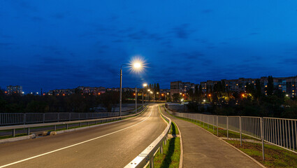Night city panorama with long exposure shining lights and road 