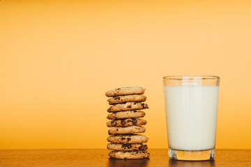 Delicious Breakfast: Cookies and Milk on a Wooden Table with an Orange Background.