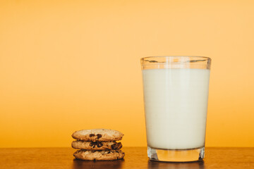Delicious Breakfast: Cookies and Milk on a Wooden Table with an Orange Background.
