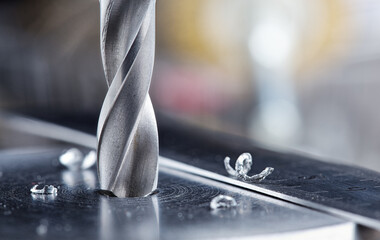 metal drill bit make holes in steel billet on industrial drilling machine
