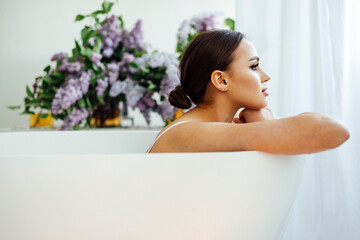 Woman folding arms on a hot tub and placing her chin on them while sitting with smile,