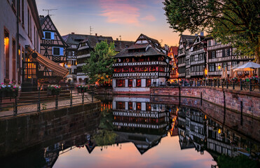 Ornate traditional half timbered houses with blooming flowers along the canals in the Petite France district of Strasbourg, Alsace, France at sunset