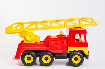 Multi-colored plastic toy trucks for children's games on a white background. Red fire truck with telescopic antenna.
