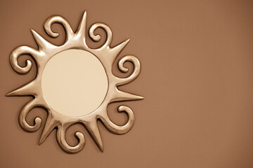 Silver sun-shaped mirror on a gray wall.