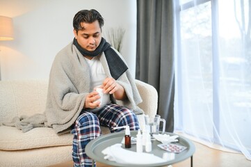 people, health and fever concept - sick indian man at home