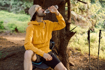 photo of a thirsty man traveling in the Carpathian forested mountains and drinking cool water from...