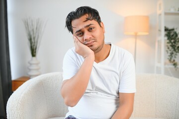 Dental problems. Young indian man touching cheek, closing eyes with expression of terrible suffer...