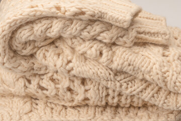 A fragment of beige knitted fabric, knitted from white sheep wool.