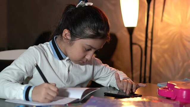 Little schoolgirl studying lessons at home