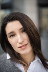 woman looking at camera walking on city street in warm spring weather