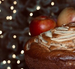 Homemade apple pie with fruit on the side with christmas tree background with out of focus lights and space for text.