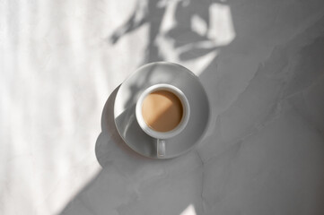 Minimal aesthetic lifestyle coffee concept, saucer and cup with milky coffee on marble gray table...