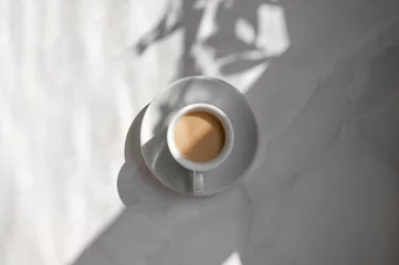 Fotobehang Minimal aesthetic lifestyle coffee concept, saucer and cup with milky coffee on marble gray table background with natural geometric sunlight shadow, good morning business branding backdrop © Viktoriia