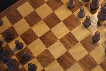 A close up photo of a handmade wooden chess board and chess pieces. 