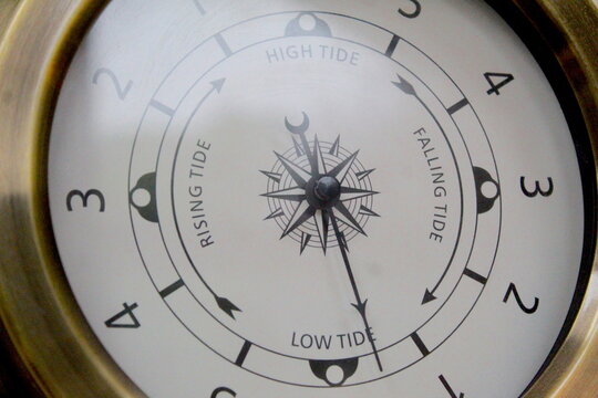 Dublin, Ireland - January 3rd 2024: A close up photo of a bronze metallic tide clock handing on the wall. 