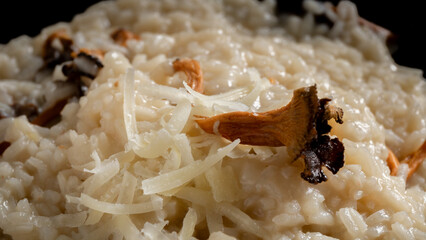 Horizontal photo detail creamy risotto with wild trumpets and parmesan. Food and gastronomy concept.