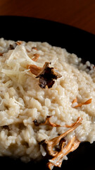 Vertical photo detail, creamy risotto with wild trumpets and parmesan. Food and gastronomy concept.