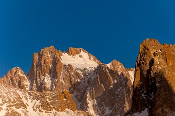 Fototapeta na wymiar Korona Peak, with rugged, snow-laced cliffs, towers under the blue sky, a beacon for climbers worldwide