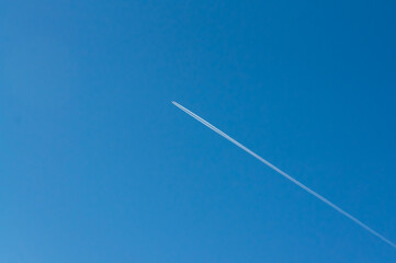A plane leaves a white contrail across the clear blue sky, a sign of travel and distant journeys.