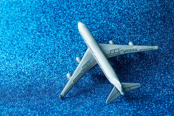 Model of a passenger plane - airliner on a sparkling blue background. Simulation of flight in the sky. Relocation, vacation or air travel concept. Copy space. Photo. Selective focus.