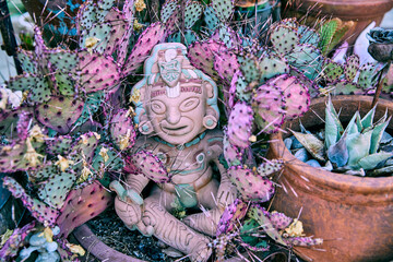 An Aztec or Mayan god or warrior in a gardening pot surrounded by cacti