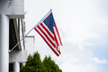 Fototapeta premium American flag hanging from a flag pole on a facade.
