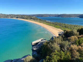 Narrow peninsular is surrounded by water on two sides. Panorama of the ocean. View of the mountain and the island's coastline. Palm beach, Australia, NSW. Beach that divides the ocean.