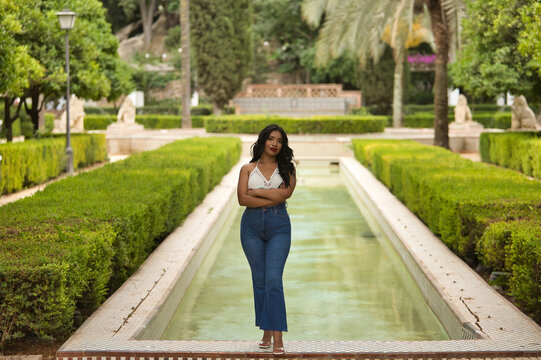 South American woman, young, beautiful, brunette, with crochet top and jeans standing next to a fountain, independent and empowered. Concept of beauty, fashion, trend, ethnicity, diversity.