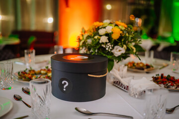 close-up view of a dining table at a formal event. The table is adorned with a vibrant floral centerpiece featuring yellow and white flowers, including roses and chrysanthemums