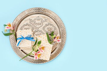 Passover Seder plate with flatbread matza and flowers on color background
