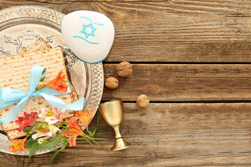 Passover Seder plate with flatbread matza, kippah, wine cup, walnuts and alstroemeria flowers on wooden background