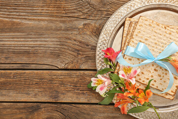 Passover Seder plate with flatbread matza and alstroemeria flowers on wooden background