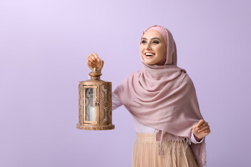 Young Muslim woman with lantern on lilac background. Islamic New Year celebration