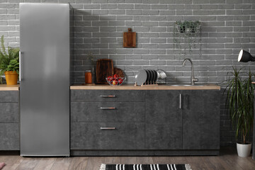 Interior of modern kitchen with grey counters, fridge and houseplants
